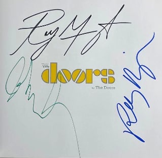 The Doors Group Signed "Doors by The Doors" First Edition Book (Third Party Guaranteed): Color hardcover 11" x 11" first edition book signed on the inside front page in green, black, and blue felt tip marker by The Doors band members Ray Manzarek, Robby Krieger, and John Densmore. In