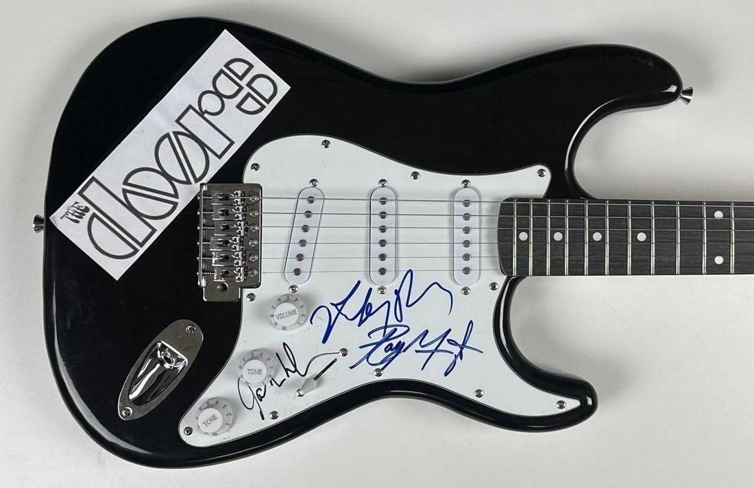 The Doors Group Signed Signature Edition Stratocaster-Style Electric Guitar (3 Sigs) (JSA): Black Stratocaster-style electric guitar signed on the pickguard in black and blue felt tip markers by The Doors band members Ray Manzarek, Robby Krieger, and John Densmore. Measuring approximately