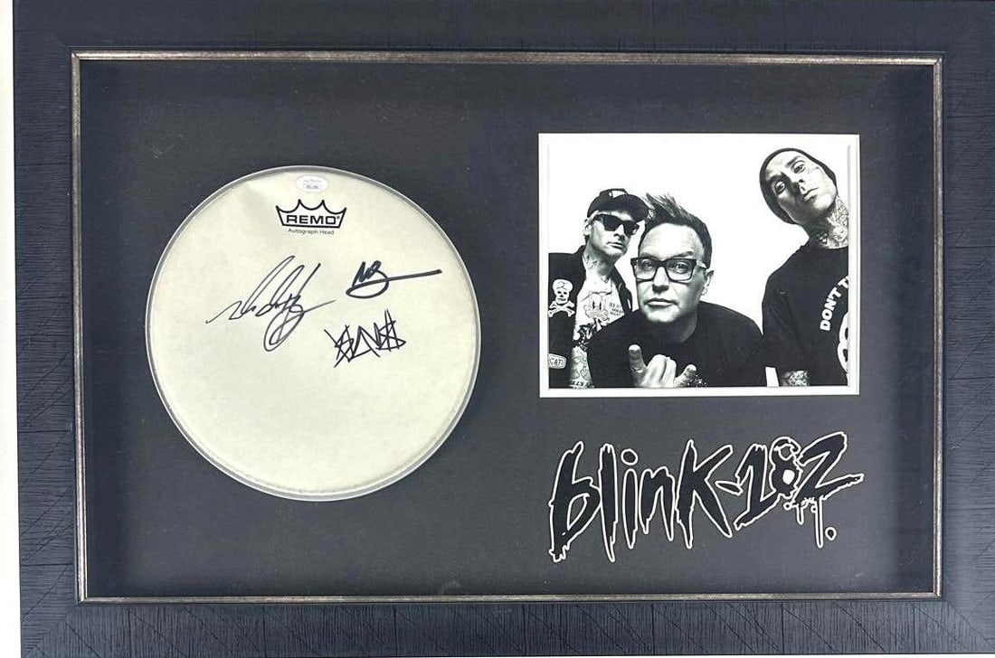 Blink-182 Group Signed 10.5" Remo Brand Drumhead Framed Display (3 Sigs) (JSA): Black-and-white framed display consisting of one signed drumhead, one unsigned photo, and one piece of stylized text reading "Blink-182" below them. White 10.5" x 10.5" Remo brand drumhead signed on