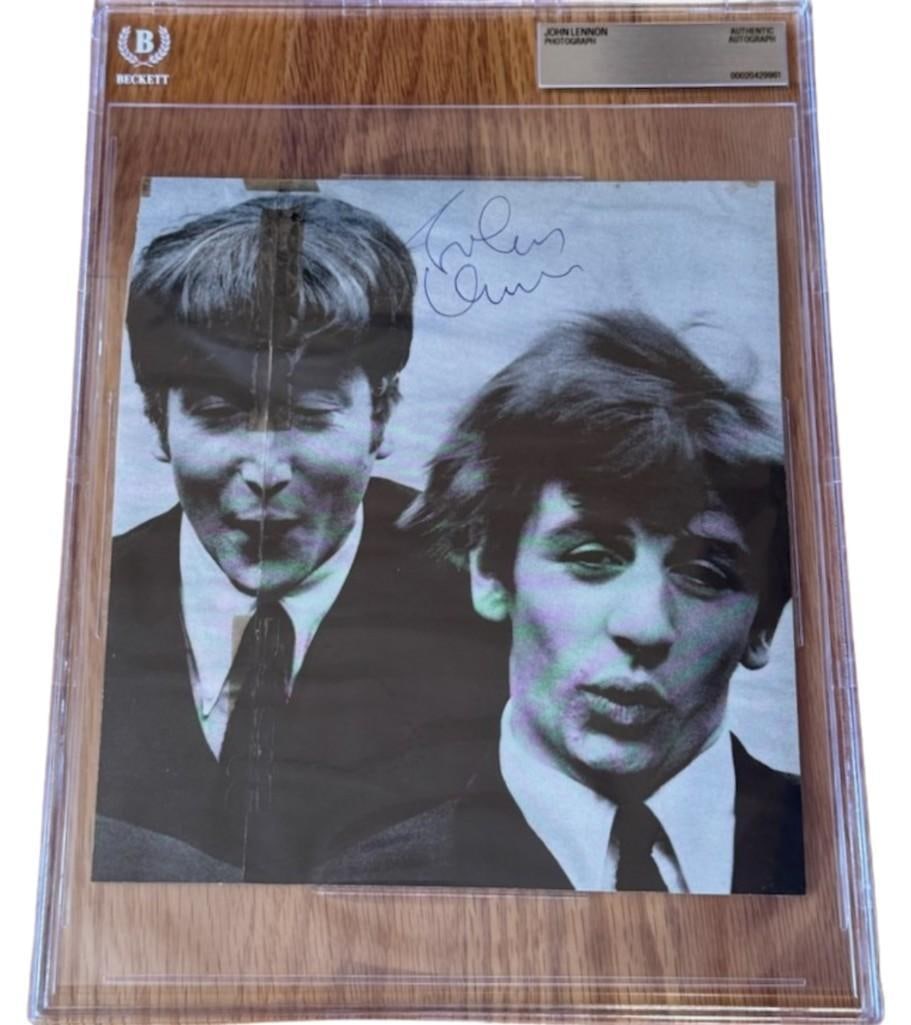 The Beatles: John Lennon Signed 7.5" x 8.5" Photo (Beckett Encapsualted): Black-and-white 7.5" x 8.5" photo signed in black ballpoint pen by the Beatles band member John Lennon. In very good condition, with some signs of scattered wear, including some creasing and tears