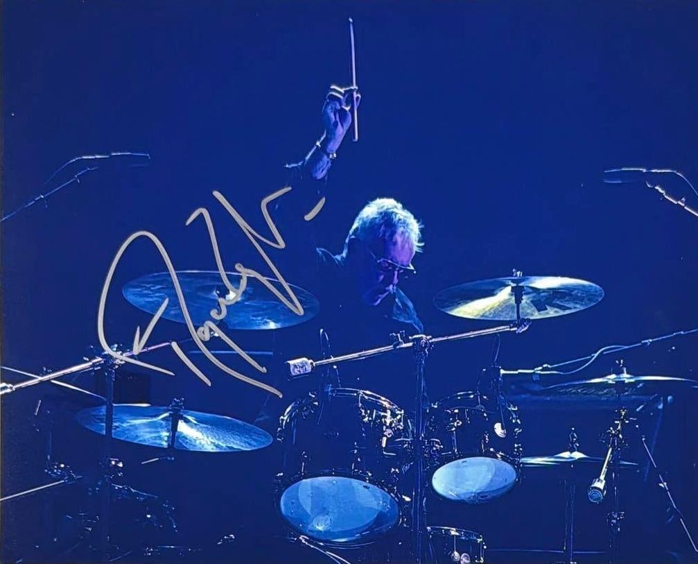 Queen: Roger Taylor Signed 8" x 10" Photo (JSA Authentication): Color 8" x 10" photo signed in silver felt tip marker by Queen band member Roger Taylor. In very good condition, with one piece of archival tape on the reverse top edge, not affecting the signature.