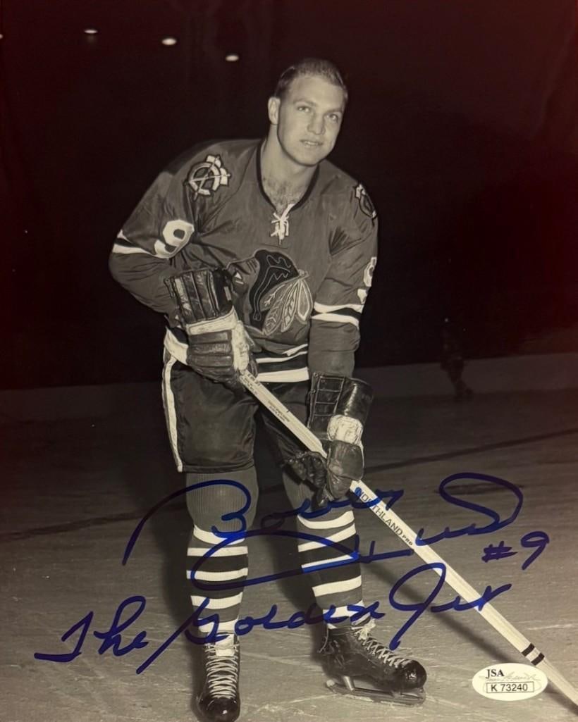 Bobby Hull Signed 10" x 8" Photo (JSA Authentication): Black-and-white 10" x 8" photo signed in blue felt tip marker by professional ice hockey player Bobby Hull, who inscribed "The Golden Rocket #9" after his signature. In fine condition. Accompanied by 