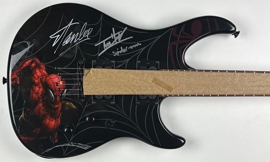 Marvel: Stan Lee & Tom Holland Signed Spider-Man Peavey Guitar (Official Pix): Marvel Spider-Man custom graphics Peavey Stratocaster-style electric guitar, signed prominently on the body in silver felt-tip marker by legendary Marvel creator Stan Lee and actor Tom Holland, who