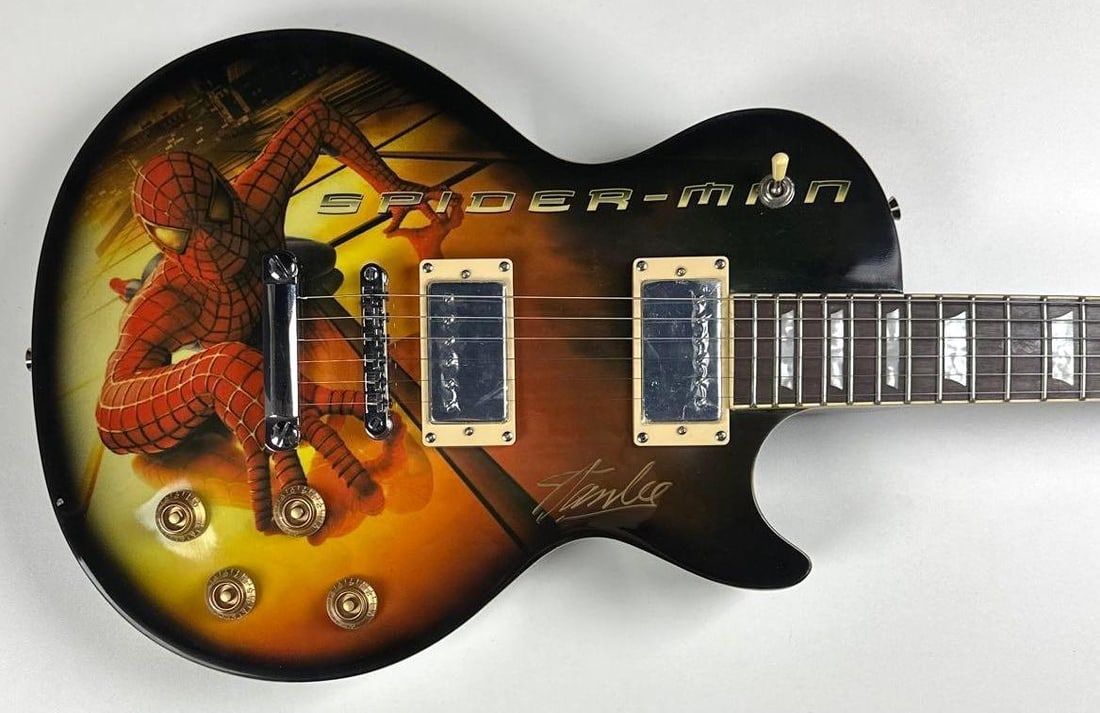 Marvel: Stan Lee Signed Spider-Man Custom Graphics Les Paul-Style Guitar (Third Party Guaranteed): "Marvel" Spider-Man custom graphics Les Paul-style guitar signed on the body in silver felt tip marker by comic writer Stan Lee. Measuring approximately 39.5" x 13" and in fine condition. Guitar accom