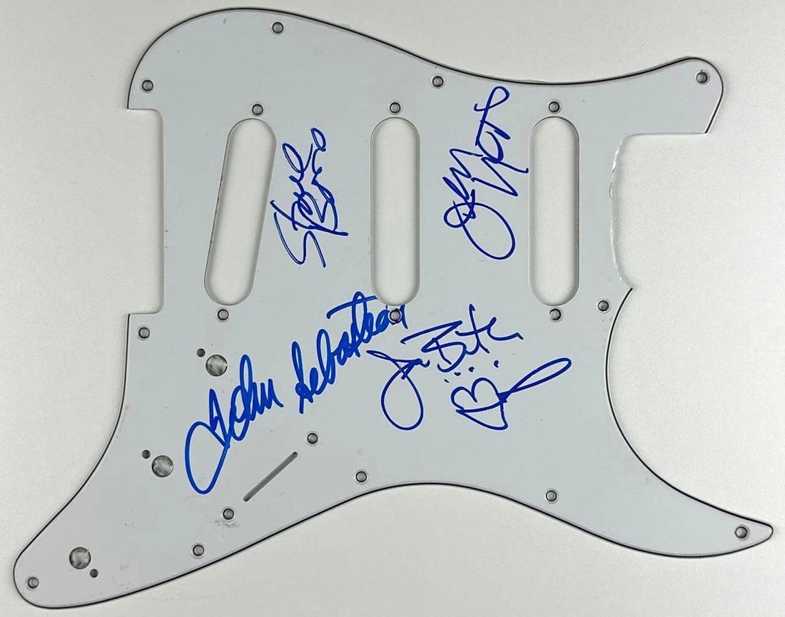 The Lovin' Spoonful Group Signed Stratocaster-Style Pickguard (4 Sigs) Third Party Guaranteed): White 9" x 11" Stratocaster-style pickguard signed on the front in blue felt tip marker by The Lovin' Spoonful band members John Sebastian, Steve Boone, Jerry Yester, and Joe Butler, who sketched a sm