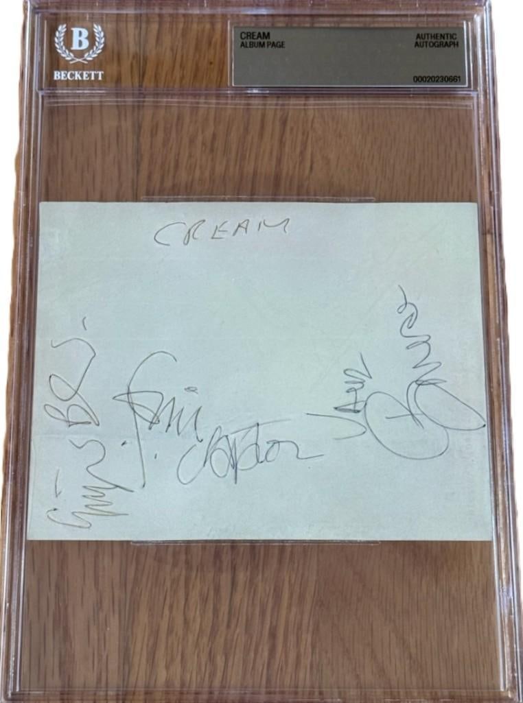 Cream Group w/ Eric Clapton Signed 4.5" x 5.5" Album Page (3 Sigs) (Beckett Encapsulated): Scarce white 4.5" x 5.5" album page signed in black and blue ballpoint pens by Cream band members Eric Clapton, Jack Bruce, and Ginger Baker, who inscribed the band name "Cream" at the top. In fine