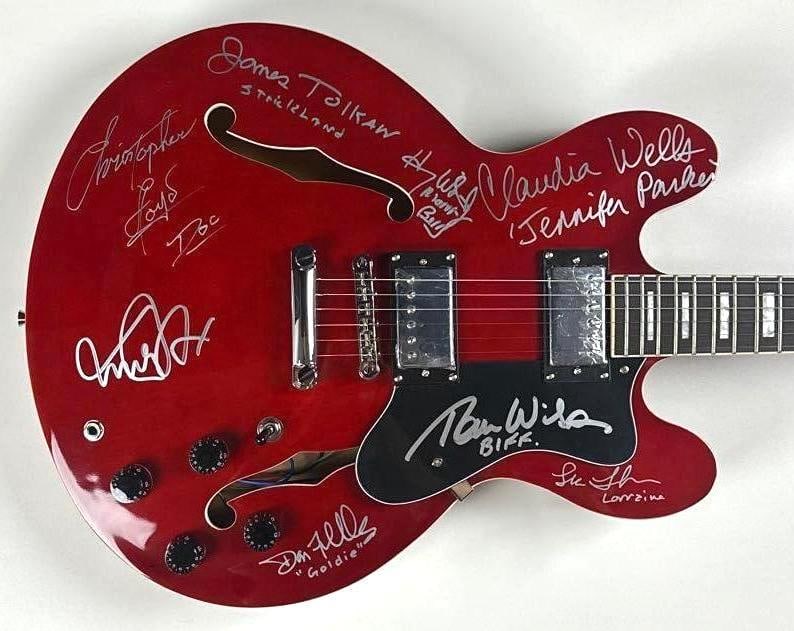 Back to the Future: Cast Signed 335-Style Semi-Hollow Guitar (7 Sigs) (Celebrity Authentics): Red 335-style semi-hollow electric guitar signed on the body and pickguard in silver felt-tip marker by seven cast members of Back to the Future: Michael J. Fox, Christopher Lloyd, Lea Thompson, James