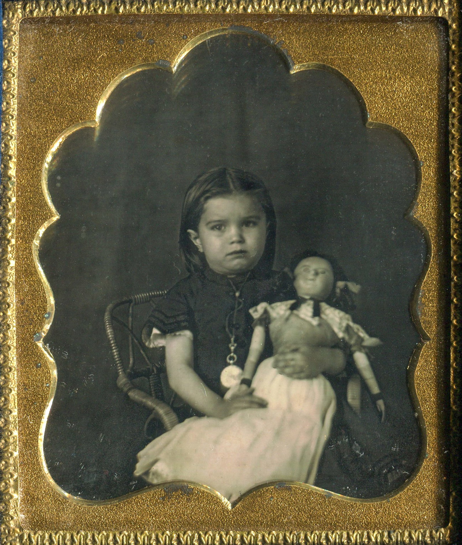 Sixth Plate Daguerreotype Portrait of a Little Girl with Her Doll.: A sixth plate daguerreotype portrait featuring a charming little girl. In this delightful image, she wears a large locket, adding a touch of elegance to the scene, while holding her cherished doll. Th