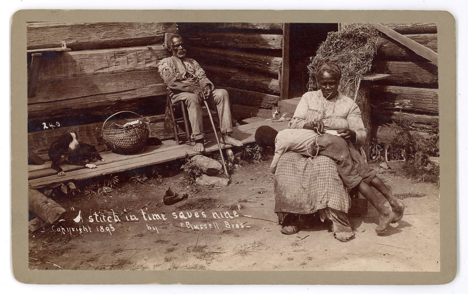 Boudoir African American Scene by Russell Brothers: Photograph copyrighted in 1895 by the Russell Brothers of Anniston, Alabama, titled “A Stitch in Time Saves Nine.” The image depicts an intimate outdoor domestic scene on the porch of a log ca