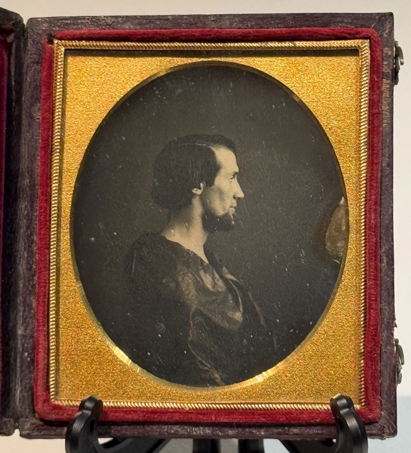 Striking Daguerreotype Profile Portrait of a Man in Robe: Sixth plate daguerreotype studio portrait of an unidentified man shown in strict profile, facing right. The image is a daguerreotype on a silvered copper plate, housed in a full leather case. The sitt