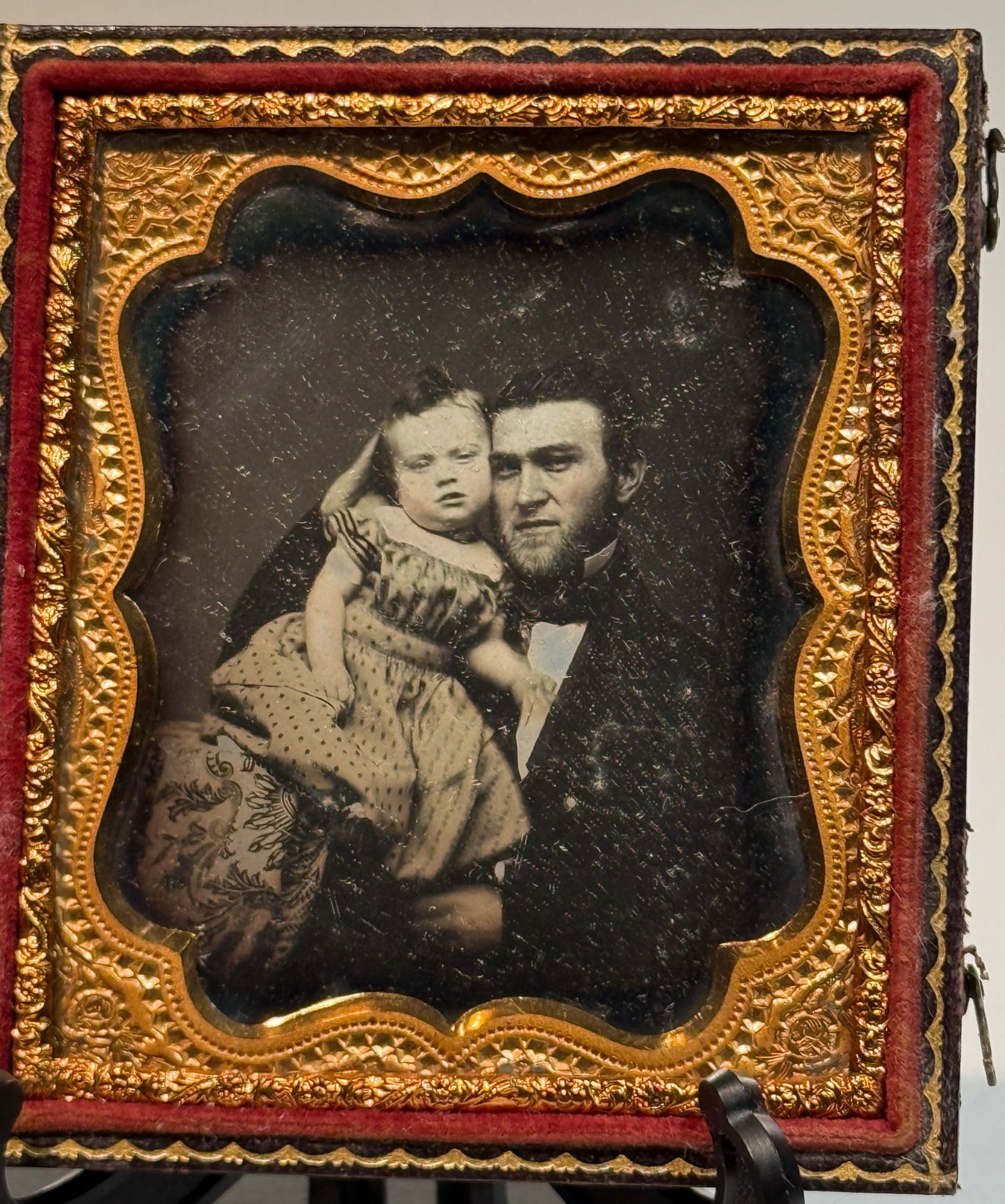 Daguerreotype Intimate Portrait of Father and Child: Daguerreotype portrait depicting an adult man holding a young child in a close, intimate studio pose. The child leans against the man’s shoulder, with the man’s arm supporting the child across the