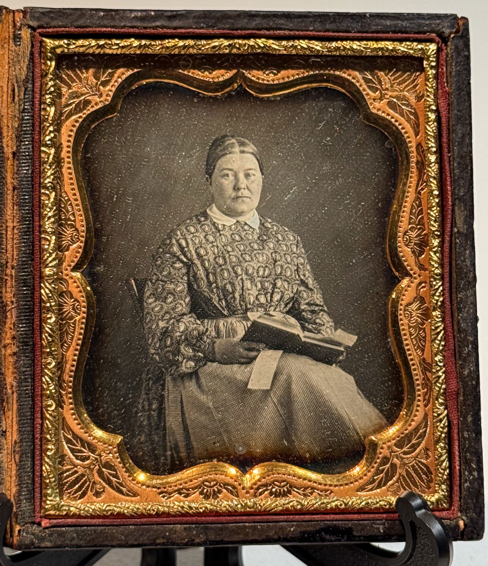 Daguerreotype of Woman Reading with Book and Notes: Sixth plate daguerreotype portrait of an unidentified woman seated indoors, holding an open book with multiple inserted paper slips used as bookmarks or notes. She wears a patterned dress with a white