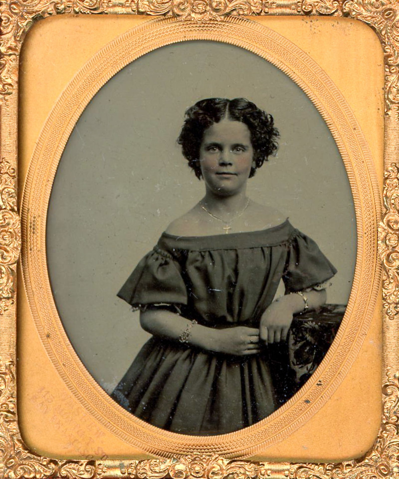 Ambrotype Portrait of a Young Woman by Wm Shew of San Francisco: Quarter plate ambrotype portrait of an unidentified young woman, photographed in a studio setting and presented in an oval brass mat. The subject is shown standing and posed with one arm resting on a