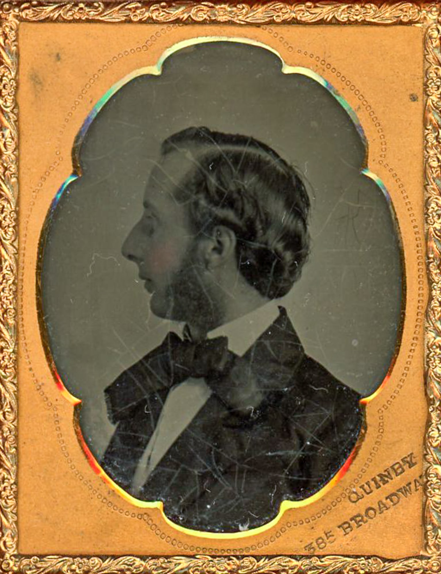 Ambrotype Profile Portrait of a Man, Quinby of NYC: Ninth plate ambrotype portrait of an unidentified man shown in strict profile, facing left, photographed in a studio setting. The image is an ambrotype on glass, presented behind a scalloped brass mat