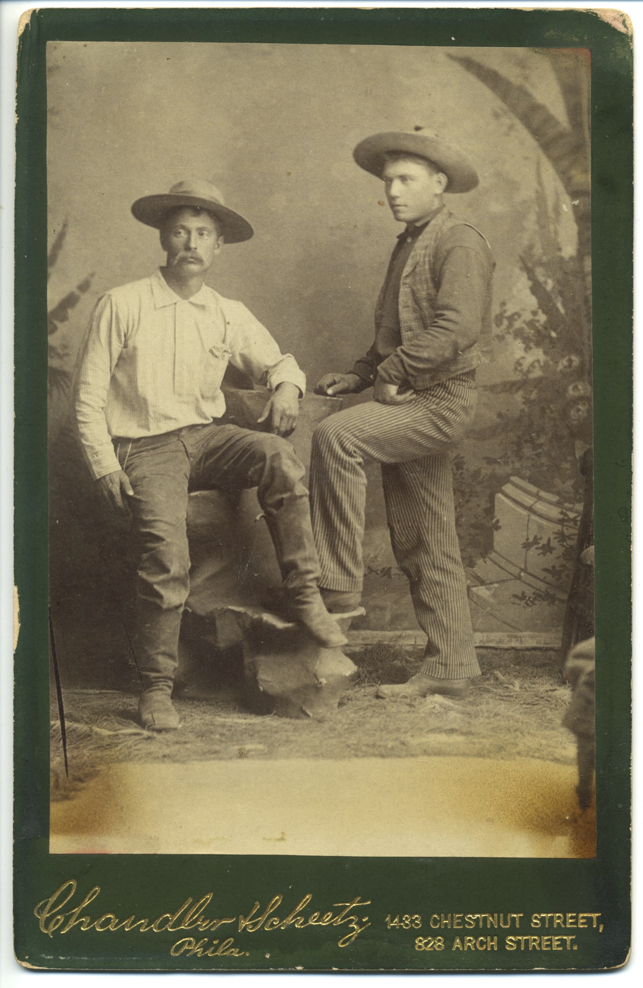 Cabinet Card of Two Men in Western Dress, Chandler & Scheetz, Philadelphia: Albumen cabinet card by Chandler & Scheetz, Philadelphia, showing two men posed in the studio wearing wide-brimmed hats and western-style clothing. Their attire, high boots, work shirts, and broad fel
