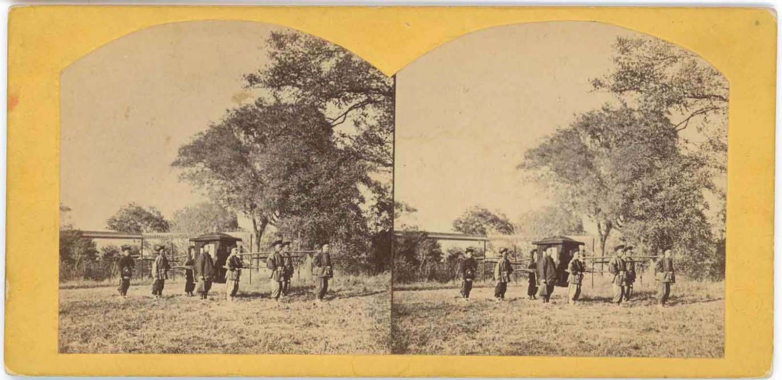 China Mandarin Sedan Chair Procession Stereoview: A finely composed albumen stereograph depicting a group of Chinese men escorting a traditional mandarin sedan chair across an open, grassy landscape. The bearers and attendants are shown in a loose li