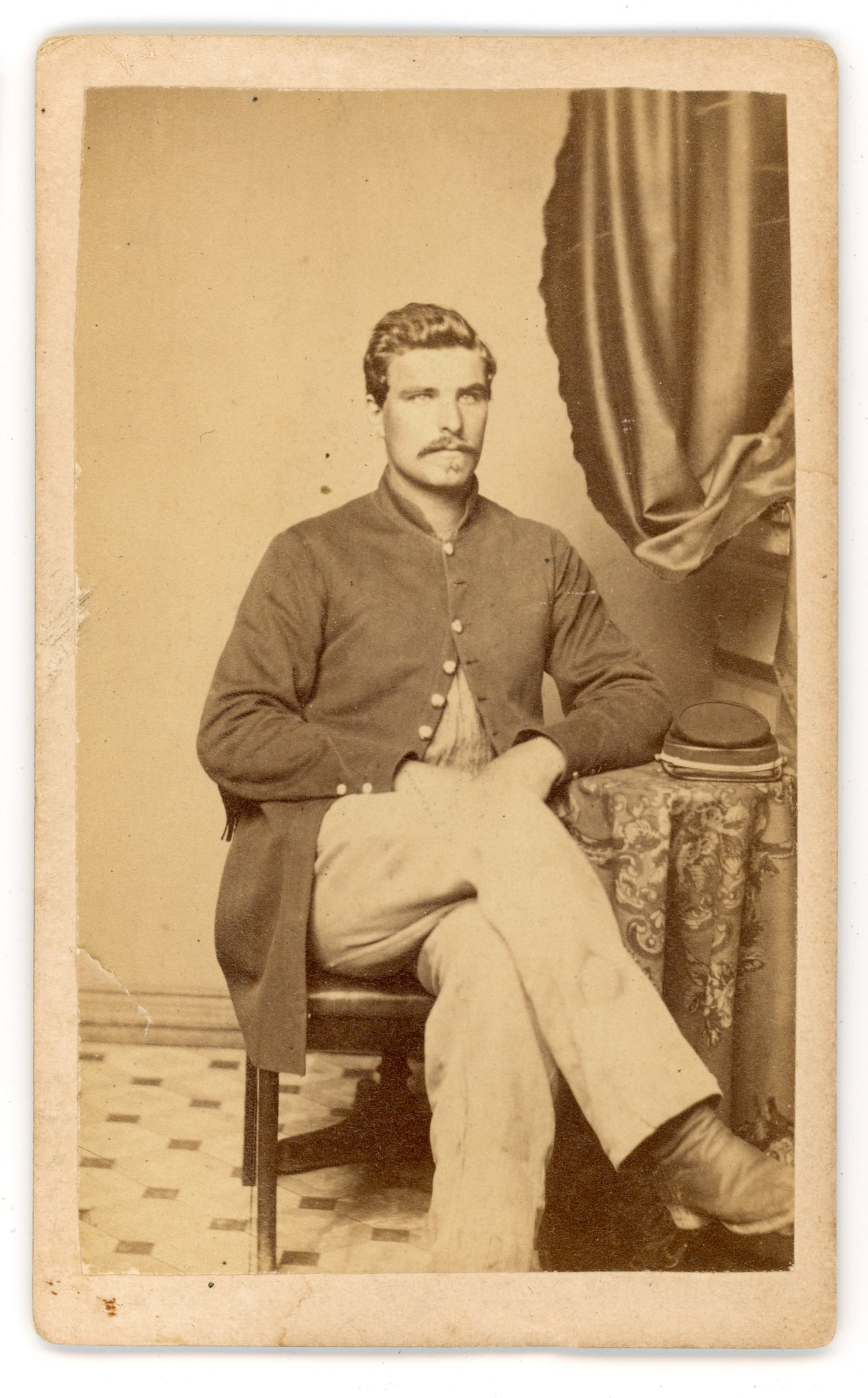 CDV Civil War Soldier Wolff Gallery Alexandria VA: Carte de visite portrait depicting a seated unidentified Union Civil War soldier wearing a military coat and posed beside a studio table with drapery backdrop. The reverse carries the imprint Wolff’