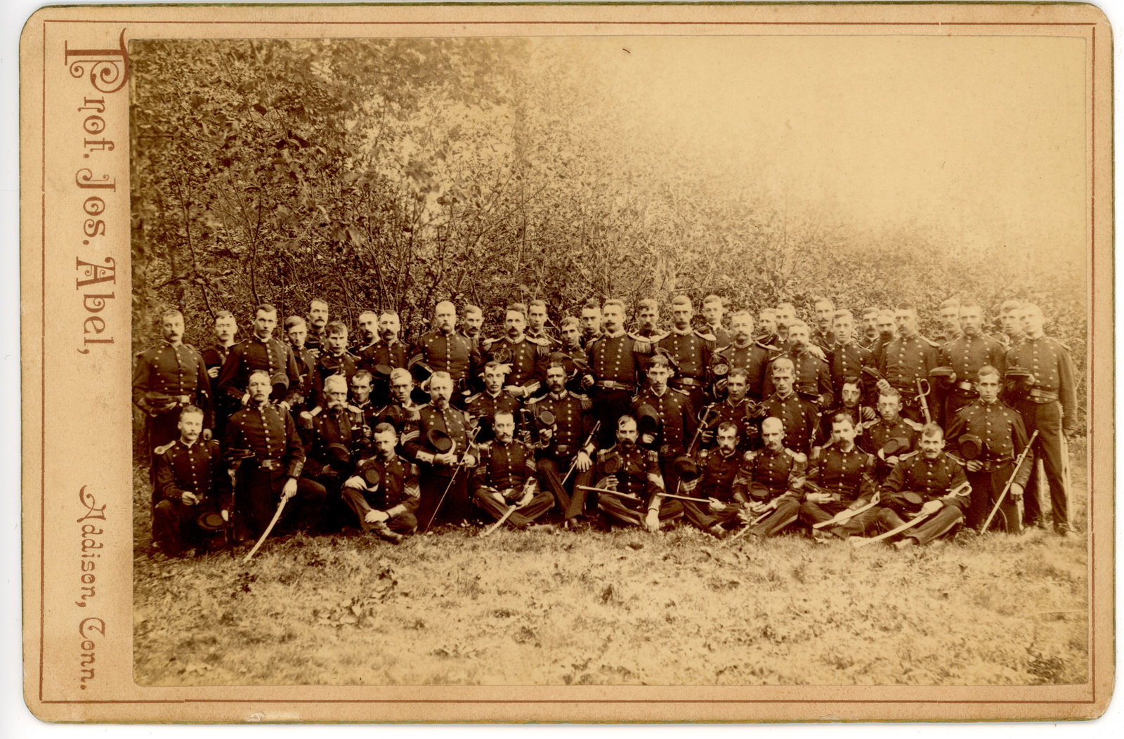 Cabinet Card Civil War Veterans Group Prof. Abel: Large cabinet card photograph depicting a sizeable group of Civil War veterans in uniform, posed outdoors in several rows. Many of the men wear military coats and several hold swords or other accoutre