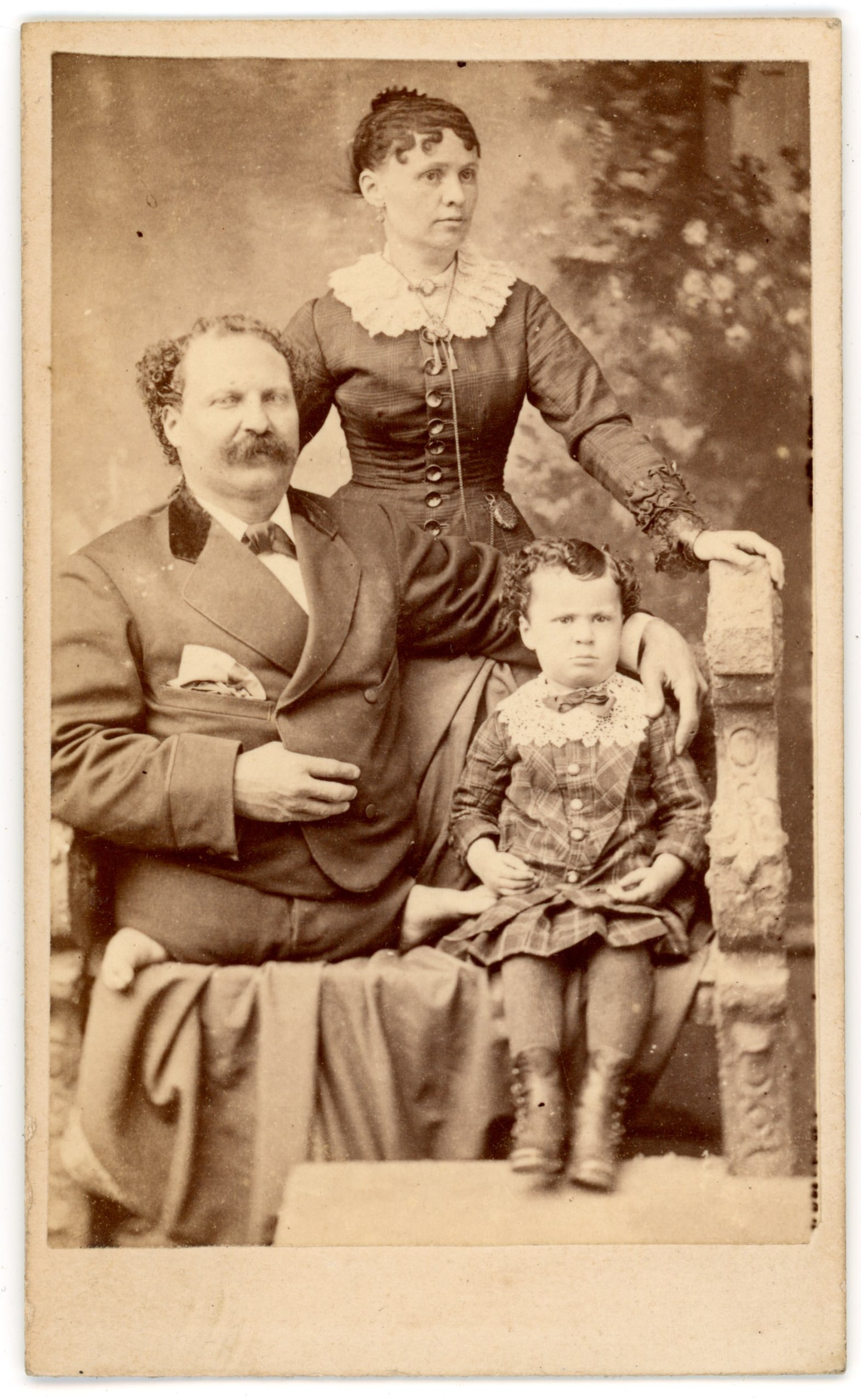 CDV "Legless" Eli Bowen Wife and Child Newman Philadelphia: Carte de visite portrait depicting Eli Bowen seated with his wife and child in a studio interior setting. Bowen was a well-known nineteenth-century sideshow performer often exhibited as the “Legless