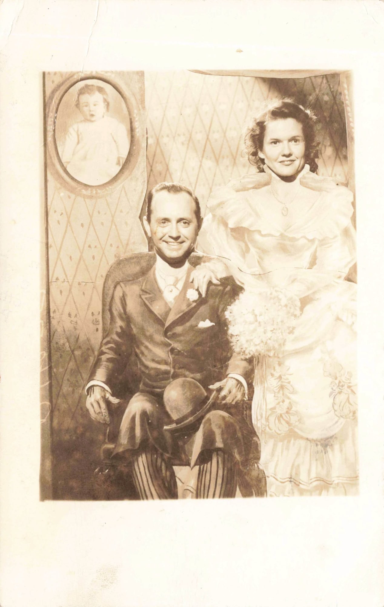 RPPC Ghost Town Gallery Comic Couple Portrait: Real photo postcard photograph depicting a posed comic portrait of a couple posed in a painted setting of a seated couple in period costumes. The coupls is posed behind the painted seting with their f