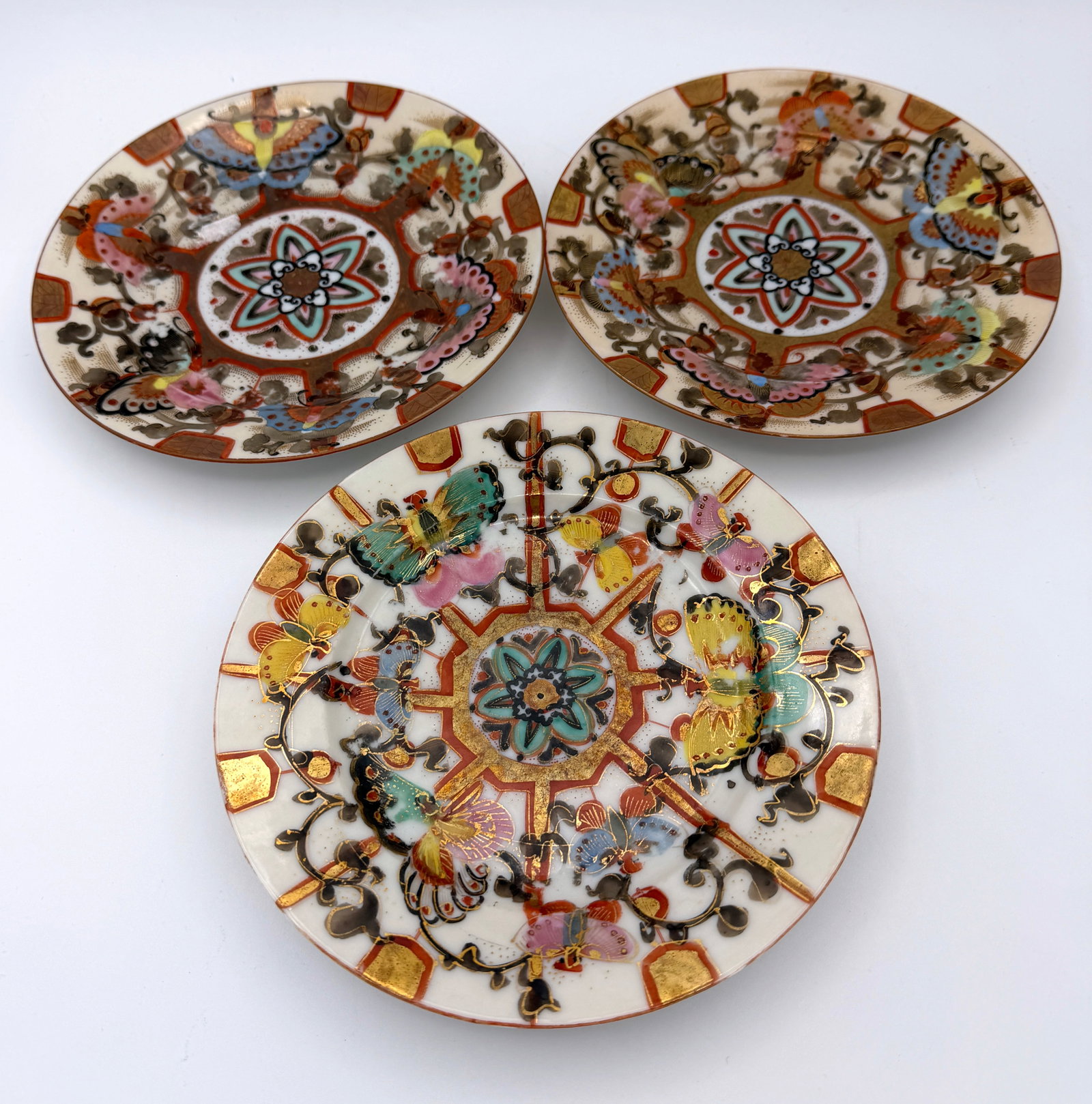 Vintage Set of 3 Kuni Oda Sei Porcelain Plates: Antique Japanese Kutani porcelain plate decorated with hand-painted butterflies and floral motifs in polychrome enamels with gilt accents. Japanese, late 19th to early 20th century.