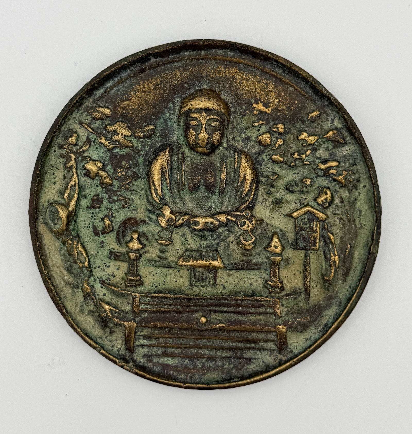 Asian Bronze Buddha Mirror Medallion: Asian circular copper-alloy medallion or mirror back, cast in relief with a seated meditating Buddha, possibly Amitabha, within a wooded temple setting. The surface has extensive green verdigris and