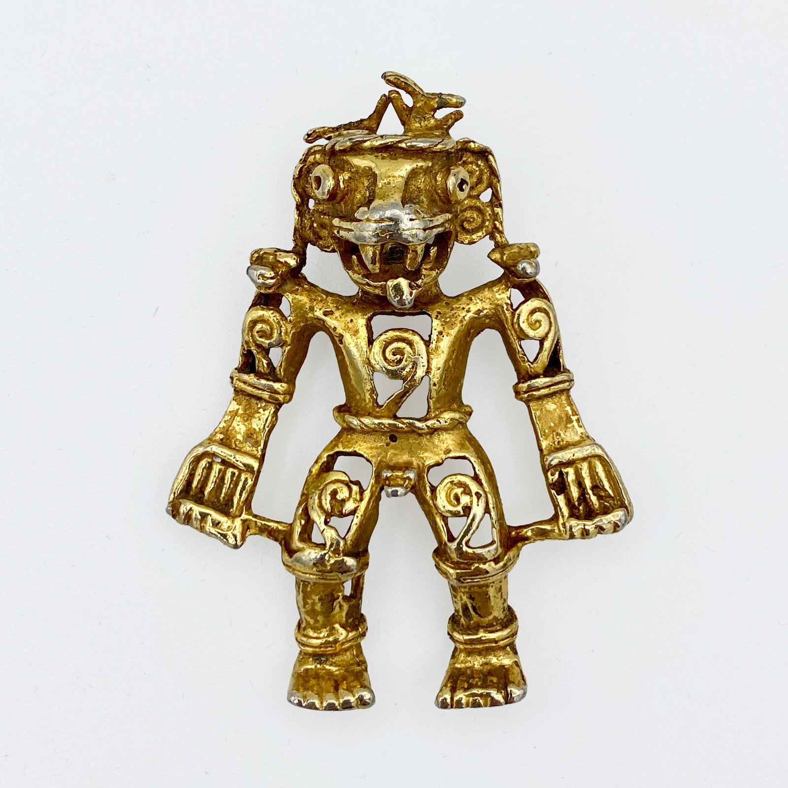 Figural Gold Tone Pendant: Large figural pendant in a pre-Columbian / Mesoamerican-inspired style reproduction, featuring an articulated, openwork figure with detailed scrollwork and stylized facial features. Gold-tone, exact