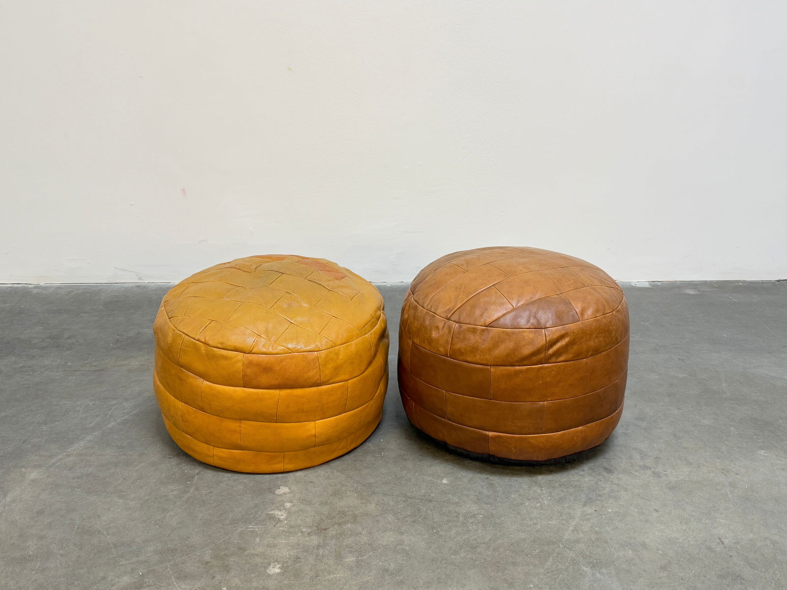 Pair of De Sede Ottomans: A luxurious pair of De Sede ottomans, upholstered in premium leather with a supple, sculptural form. Height: 15 in. Width: 20 in. Depth: 20 in.