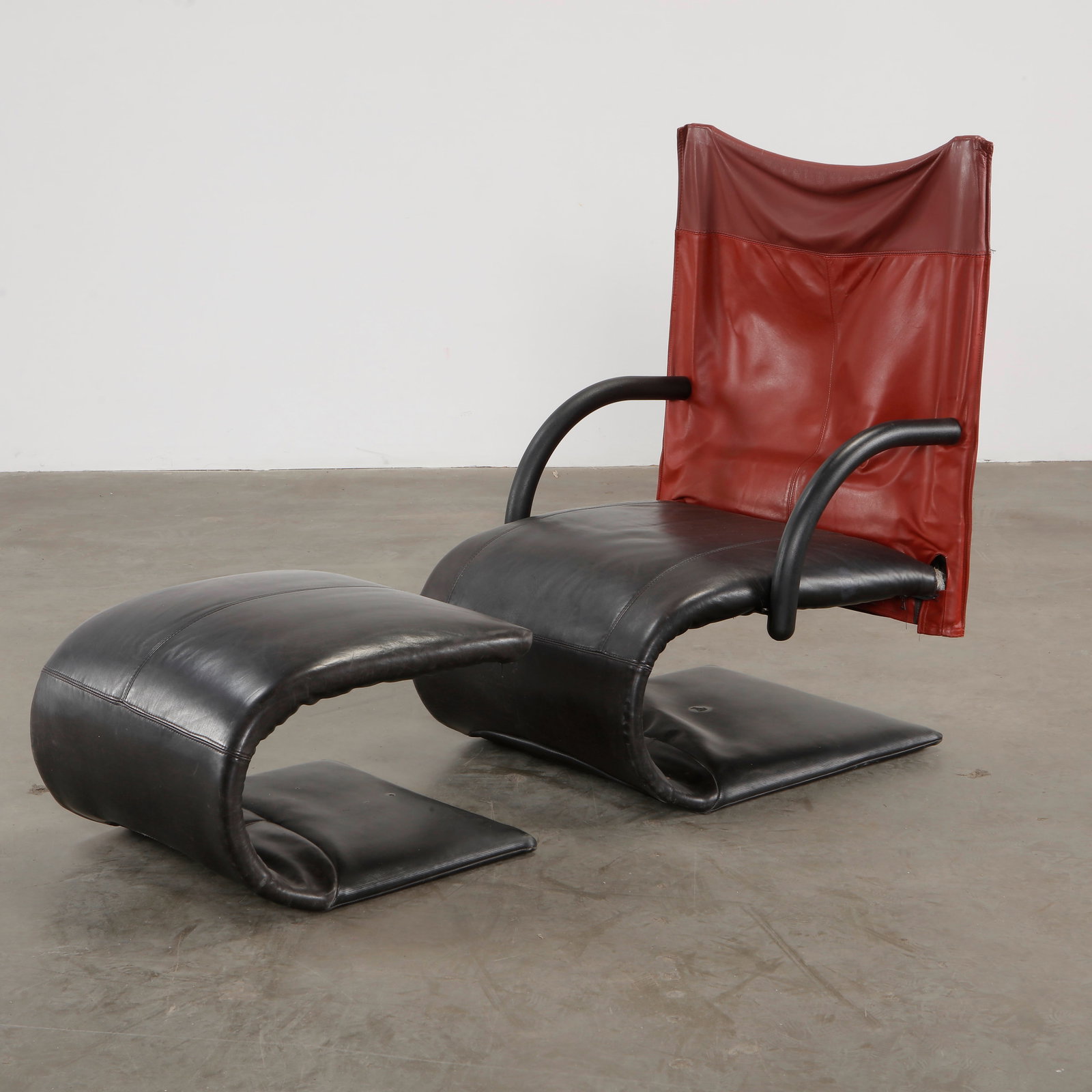 Zen Lounge Chair and Ottoman by Claude Brisson, 1980s: A striking combination of black leather and red sling back, this lounge chair and ottoman set by Claude Brisson exudes contemporary elegance with ergonomic comfort. Height: 39 in. Width: 38 in. Depth: