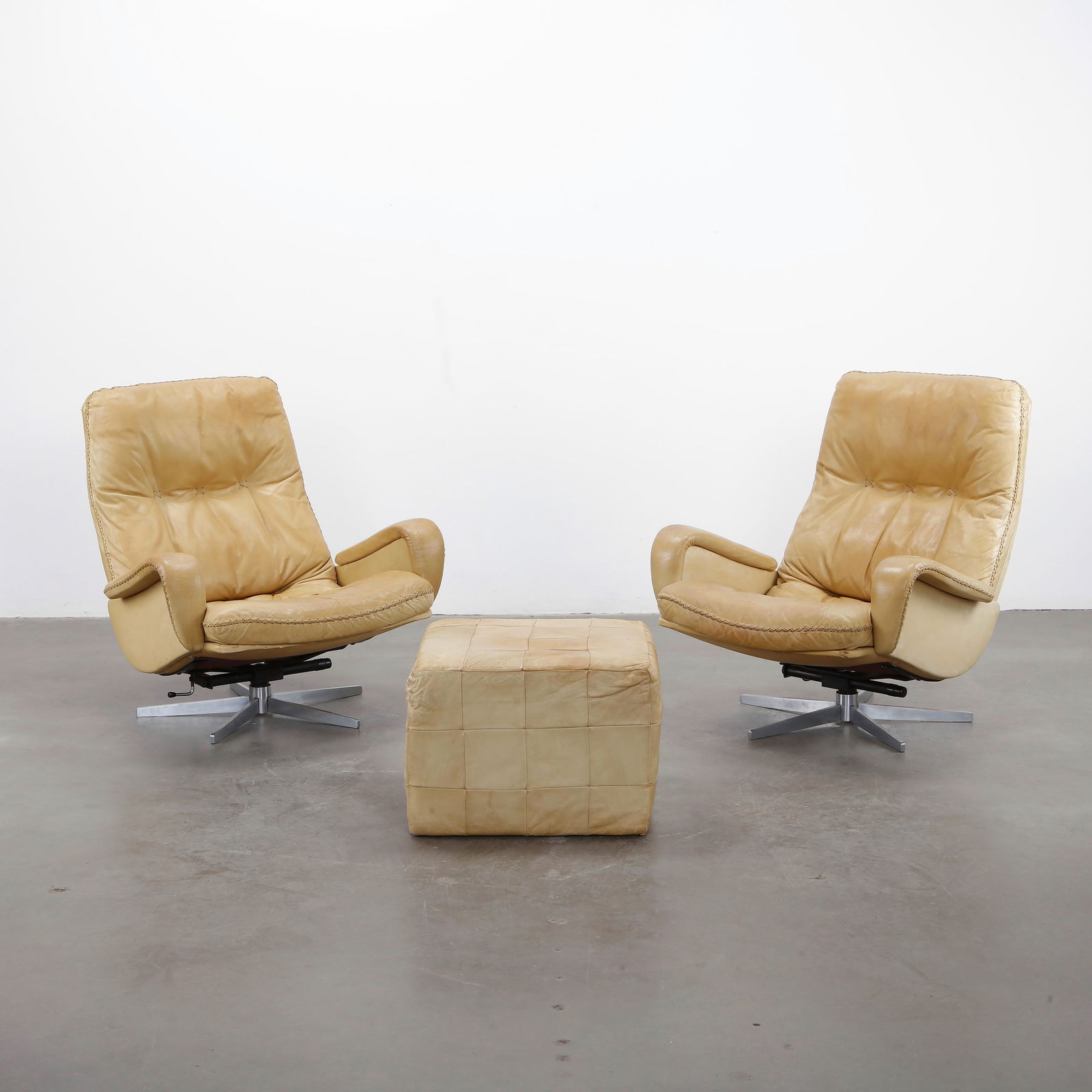 De Sede, Pair of S231 James Bond Swivel Armchairs with Ottoman, 1960s: Iconic pair of De Sede S231 swivel armchairs with matching ottoman, upholstered in patinated beige leather. Switzerland, 1960s.Height: 35 in. Width: 29 in. Depth: 24 in. Seat Height: 22 in. Otoman: He