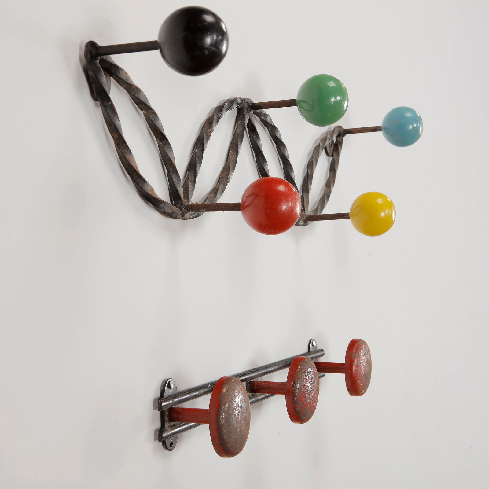 Roger Feraud, Set of Two Black and Multi-Color Coat Racks, 1960s: A pair of sculptural wall-mounted coat racks by Roger Feraud, featuring twisted iron frames with vibrant lacquered wooden hooks and industrial painted metal pegs. A striking duo blending playful mid-c