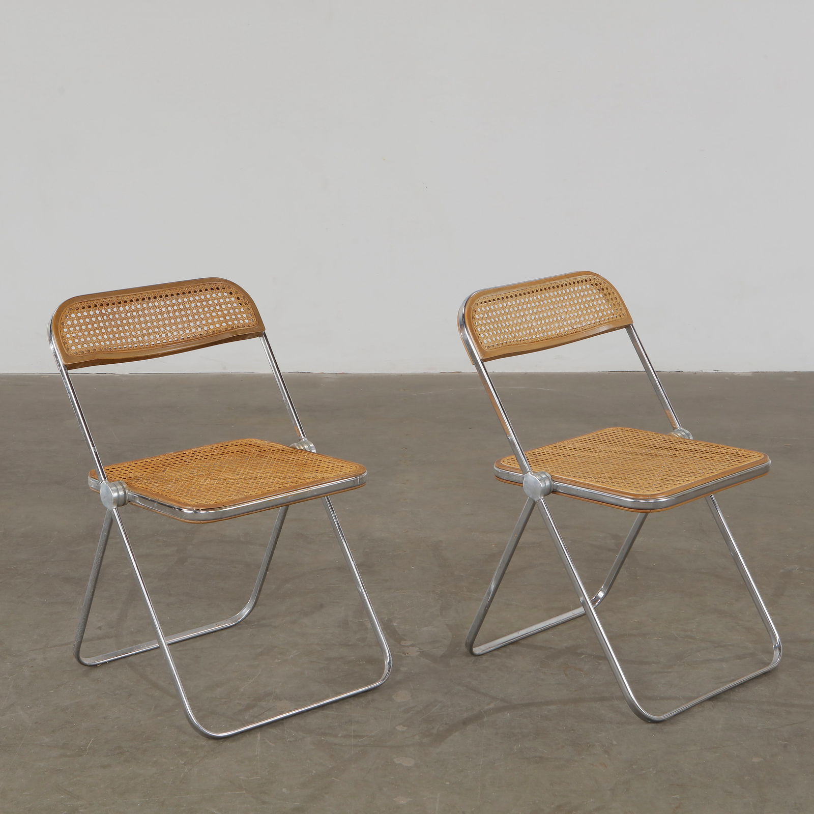 Giancarlo PIRETTI, Pair of Plia Folding Chairs in Chrome and Cane, circa 1967: An iconic innovation of Italian design, these four Plia chairs feature chromed tubular frames and caned seats, are emblematic of Piretti contribution to democratic design. Height: 29 in. Width: 18.5 i