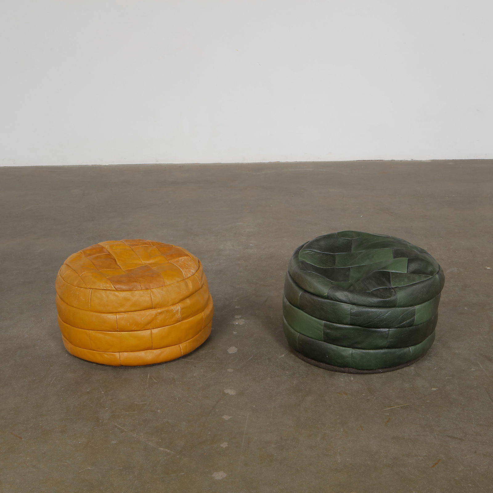 De Sede, Pair of Leather Otttomans, 1960s: Vintage De Sede leather poufs in beige and green tones. Swiss design, superb patina. Brown: Height: 14.5 in. Width: 20 in. Depth: 20 in. Green: Height: 11.5 in. Width: 20 in. Depth: 20 in.