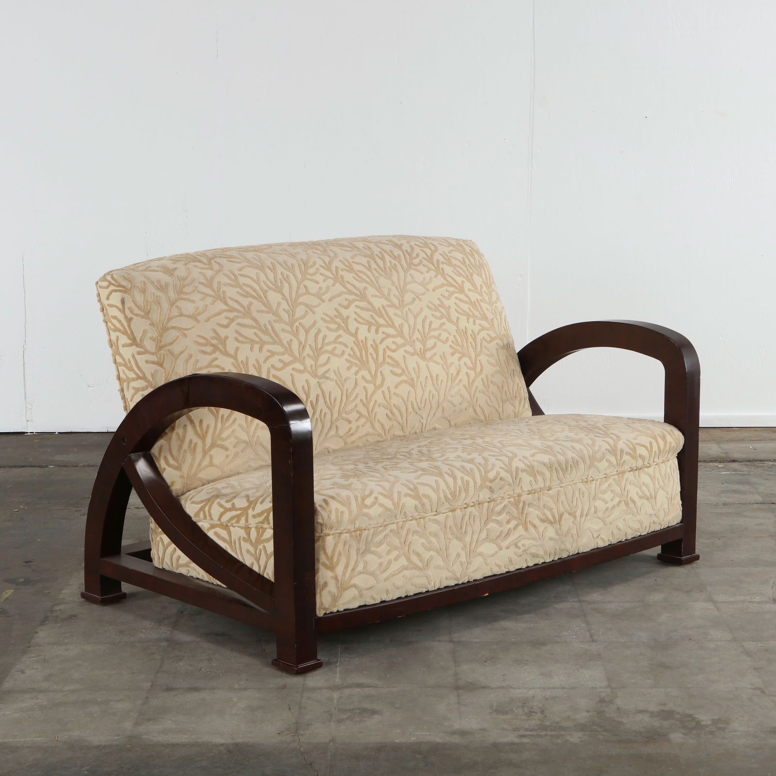 Italian Two-Seater Sofa in the style of Enrique Garcel Jaime, 1930s: Art Deco inspired sofa with bold, curved wooden arms and cream patterned upholstery, evoking early modern Italian craftsmanship. Height: 39 in. Width: 51.25 in. Depth: 30.5 in. Seat Height: 15 in. Sea