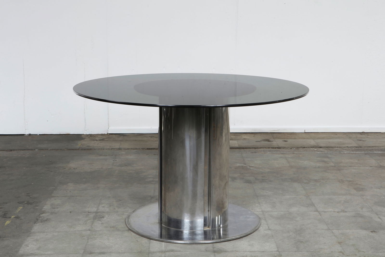 Cidonio Dining Table attriuted to Antonia Astori for Cidue, 1960s: Sleek Italian pedestal table with a smoked glass round top resting on a polished chrome cylinder base. A bold and minimalist statement of 1960s modernism. Height: 28.5 in. Diameter: 47 in.