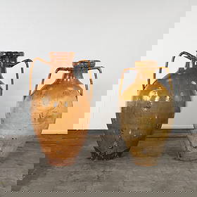 Pair of Colossal Glazed Terracotta Storage Amphorae from Puglia Region, 20th Century: Two tall Mediterranean amphora-style jars with glossy brownish glaze. Each has two handles and a spout at the bottom, typically used for storing liquids like olive oil or wine. JUG 1: Height: 49 in. D