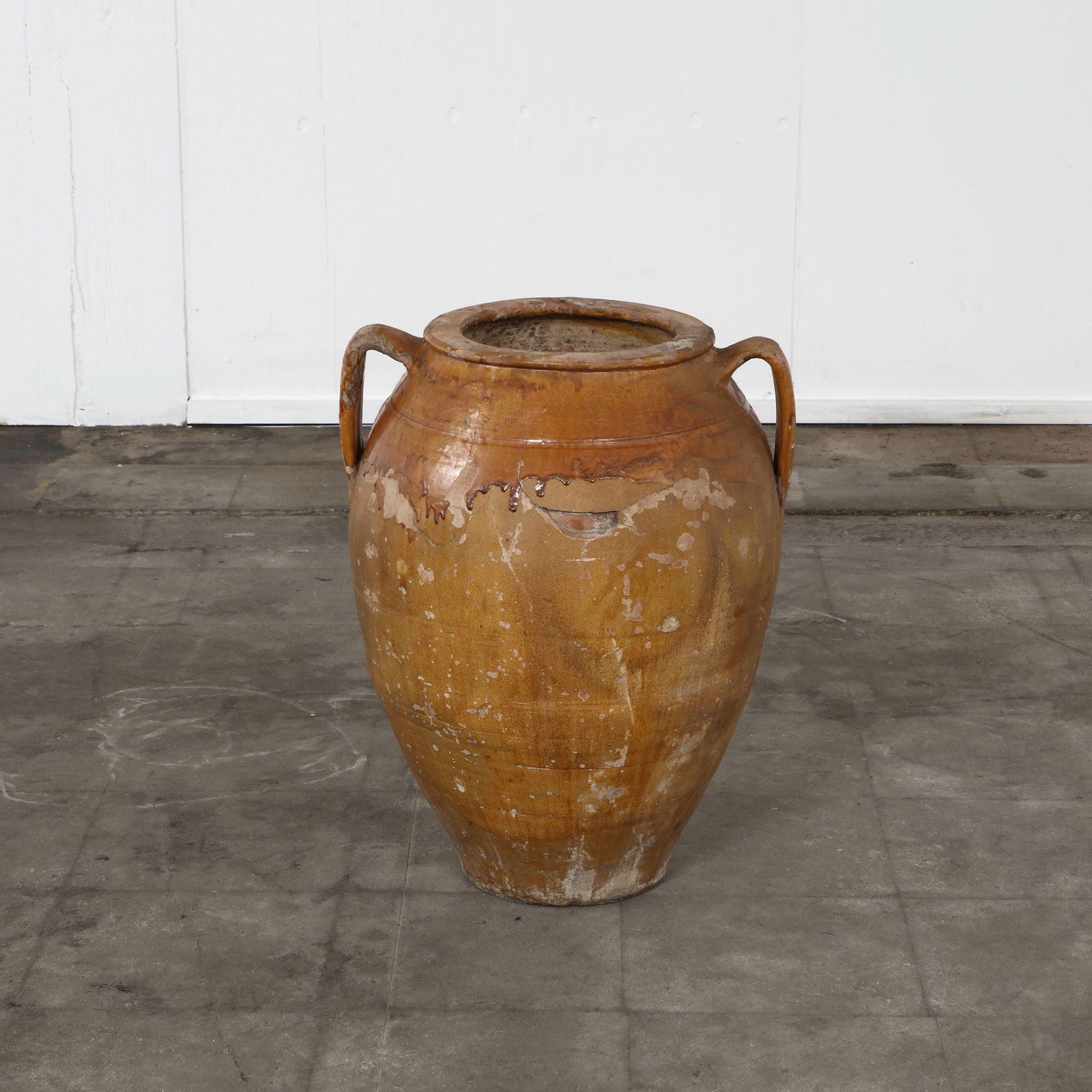 Single Large Ochre-Glazed Terracotta Amphora, Early 20th Century: A standalone amphora with handles and a wide mouth. Its ochre glaze shows signs of wear and patina, reflecting its age and authenticity. Height: 24.5 in. Diameter: 19 in. Opening Diameter: 9 in.