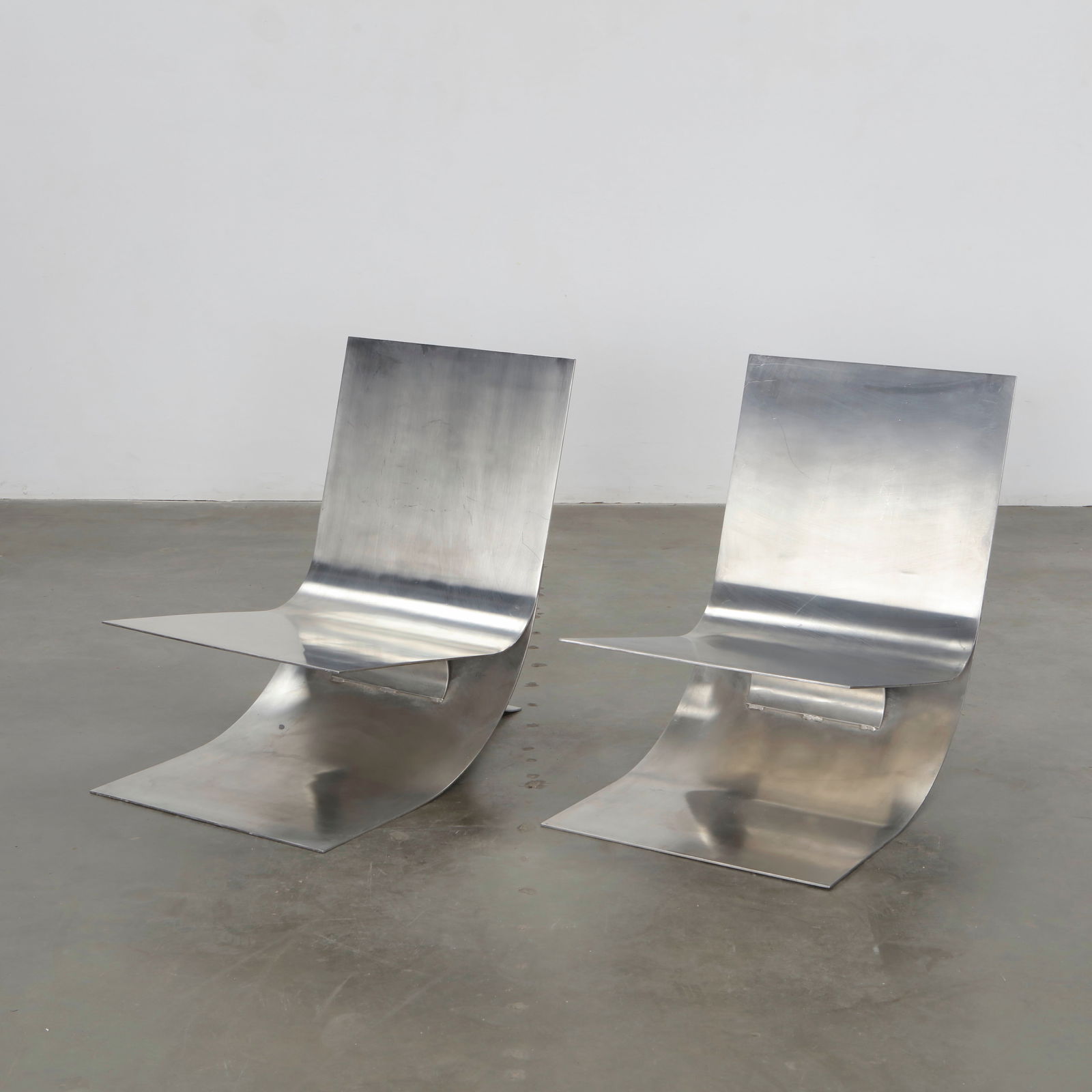 Pair of Lounge Chairs attributed to Maria Pergay, France, 1970s: Brushed stainless-steel ensemble with sinuous, folded silhouettes. The fluid lines and reflective surfaces embody Pergay radical reinterpretation of metal as a sensual, sculptural medium. Height: 30 i