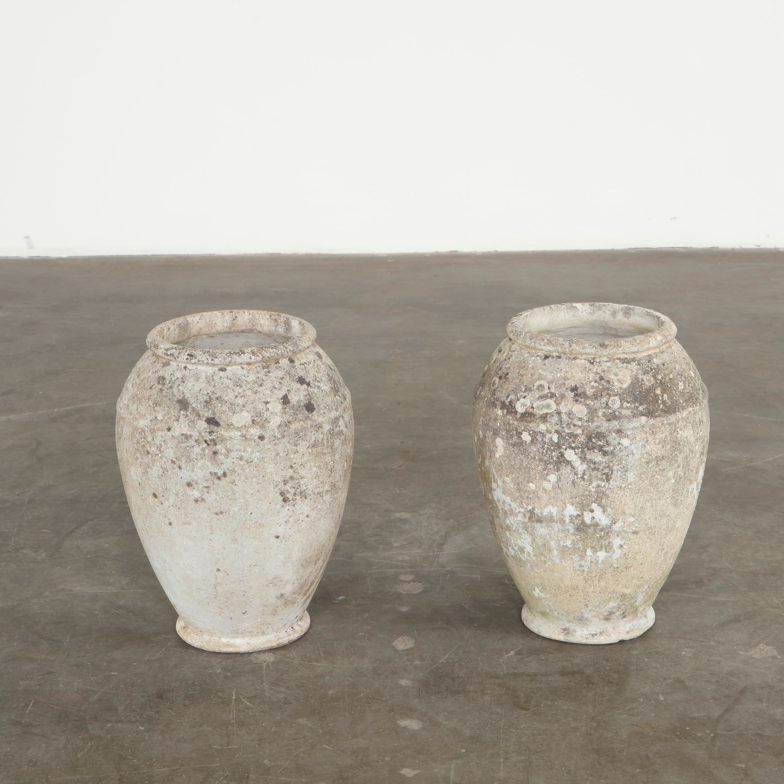 Willy Guhl, Pair of Urn Planters, 1960s: Executed in molded cement, these urn-shaped planters display generous curves and a refined classical influence interpreted through modern materials. Their weathered surfaces have developed the rich pa