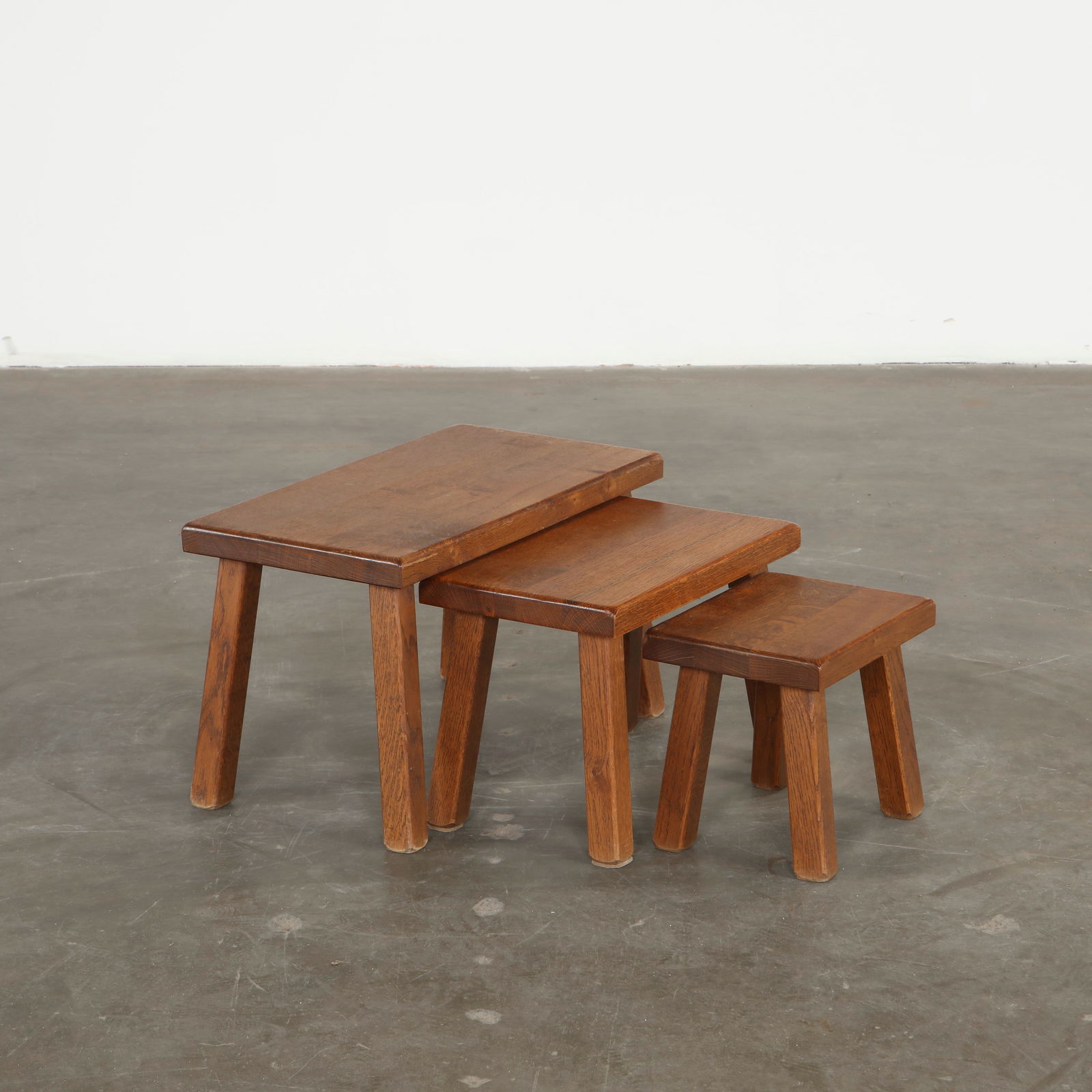 Set of Three Brutalist Oak Nesting Tables in the style of Pierre Chapo, 1950s: Crafted in oak with pronounced joinery and sculptural silhouettes, these nesting tables evoke the architectural clarity associated with Chapo early work. Their stacking design combines practicality wi