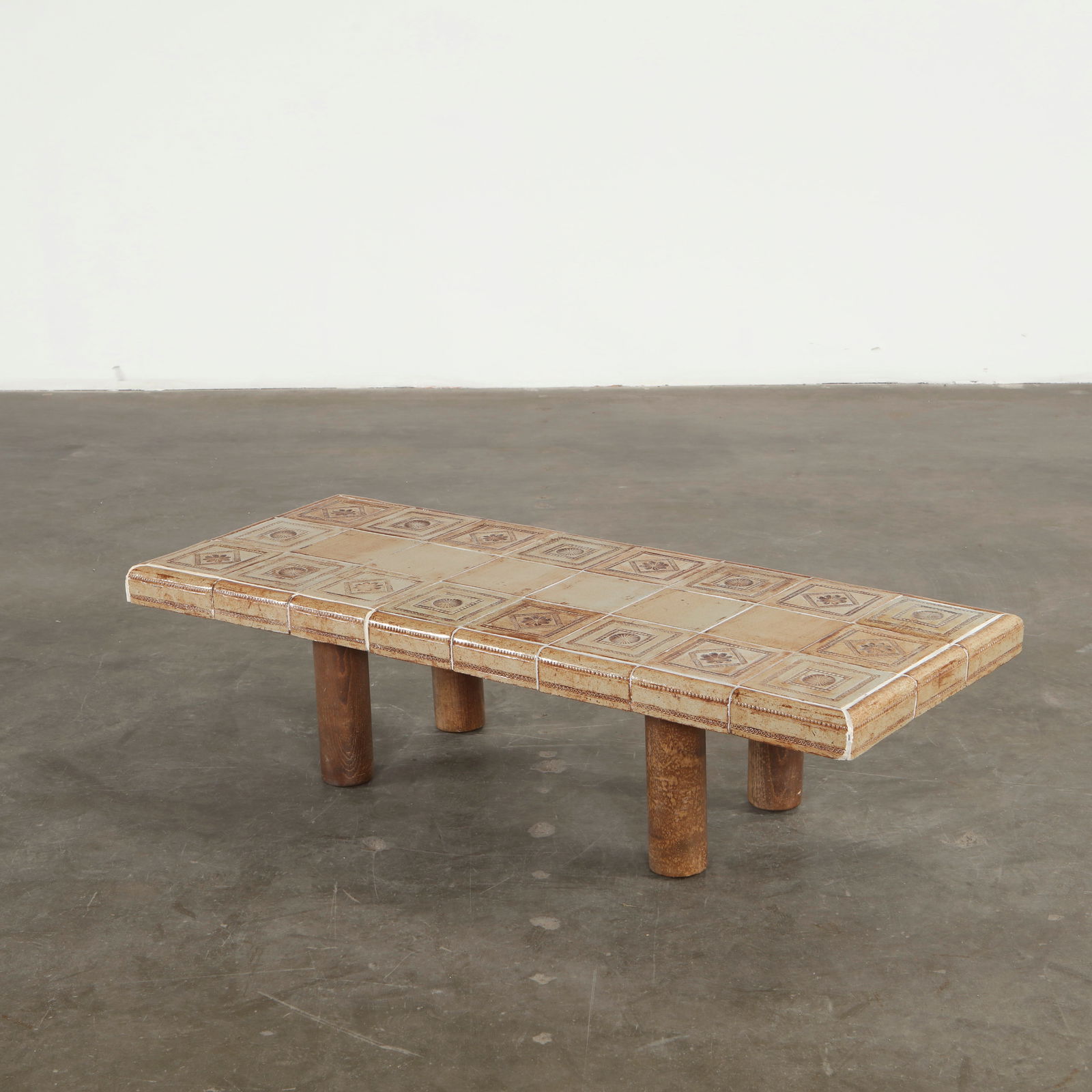 Roger Capron, Ceramic Coffee Table, 1960s: The surface is composed of hand glazed ceramic tiles with geometric and floral motifs, creating a richly textured tabletop. Supported by cylindrical wood legs, the piece demonstrates the decorative se