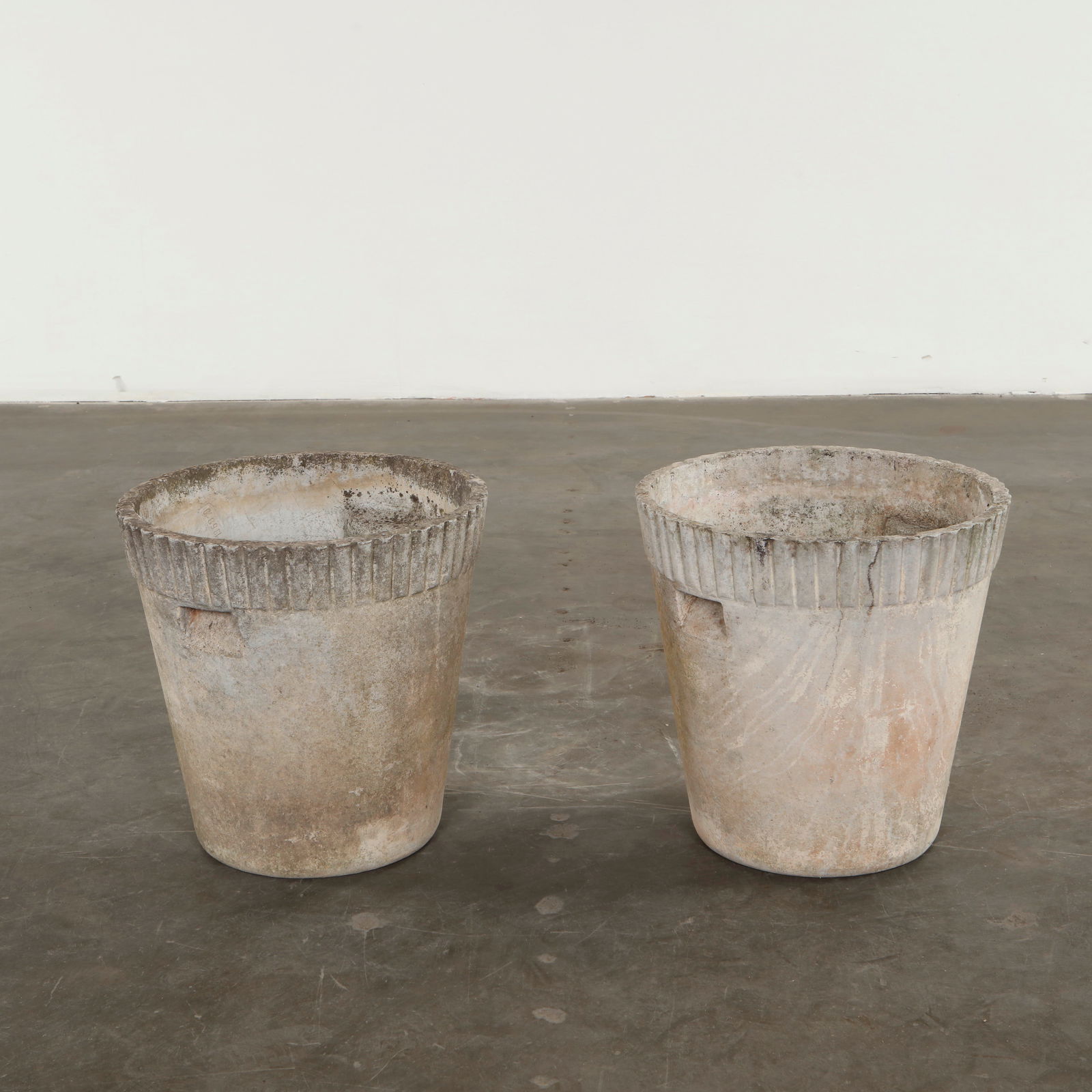 Willy Guhl, Pair of Round Planters, 1960s: Executed in textured cement, these angular planters feature sharply defined facets that play with light and shadow. The surfaces show an elegant aged finish characteristic of early Swiss production. A