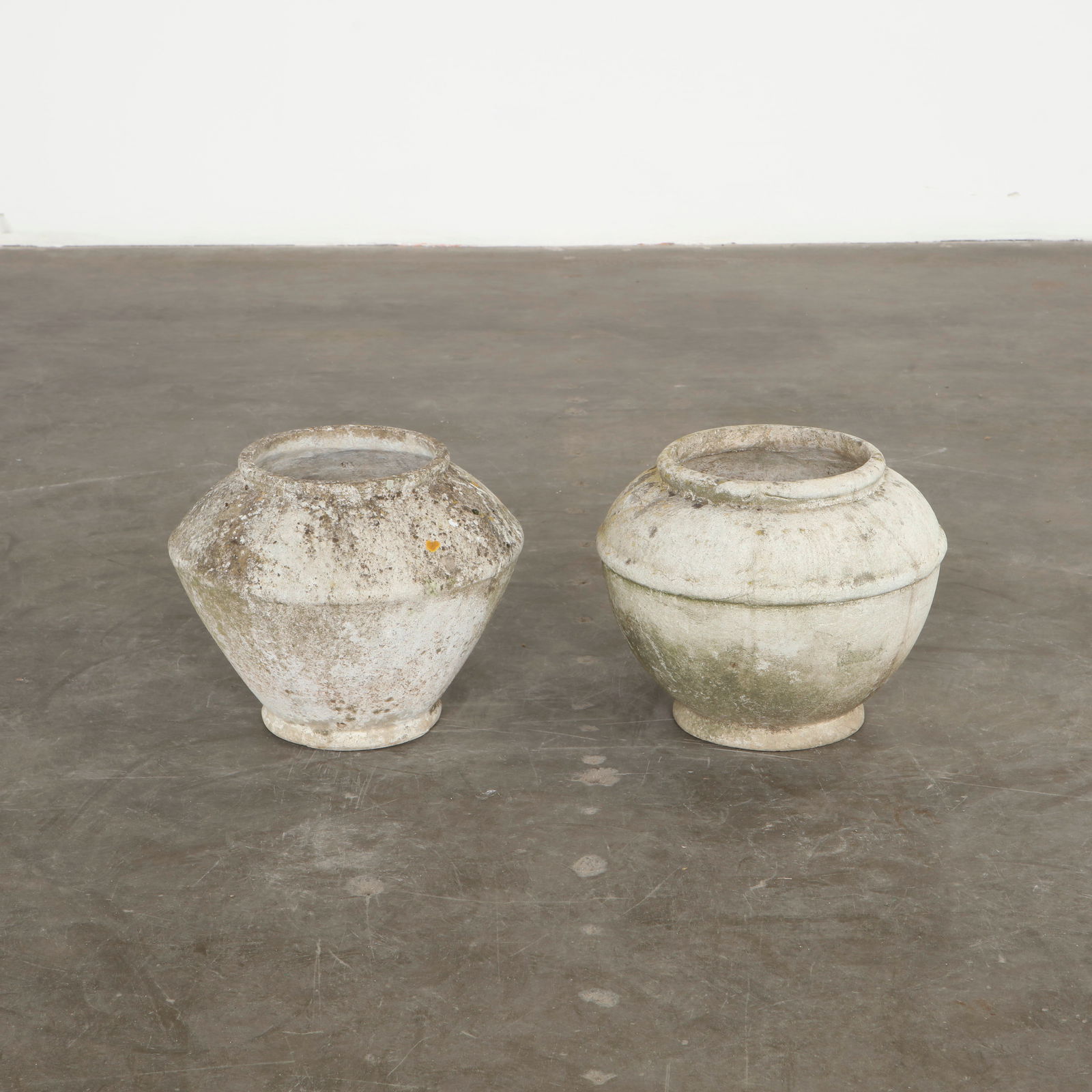 Willy Guhl, Pair of Urn Planters, 1960s: Executed in molded cement, these small urn shaped planters display generous curves and a refined classical influence interpreted through modern materials. Their weathered surfaces develop the rich pat