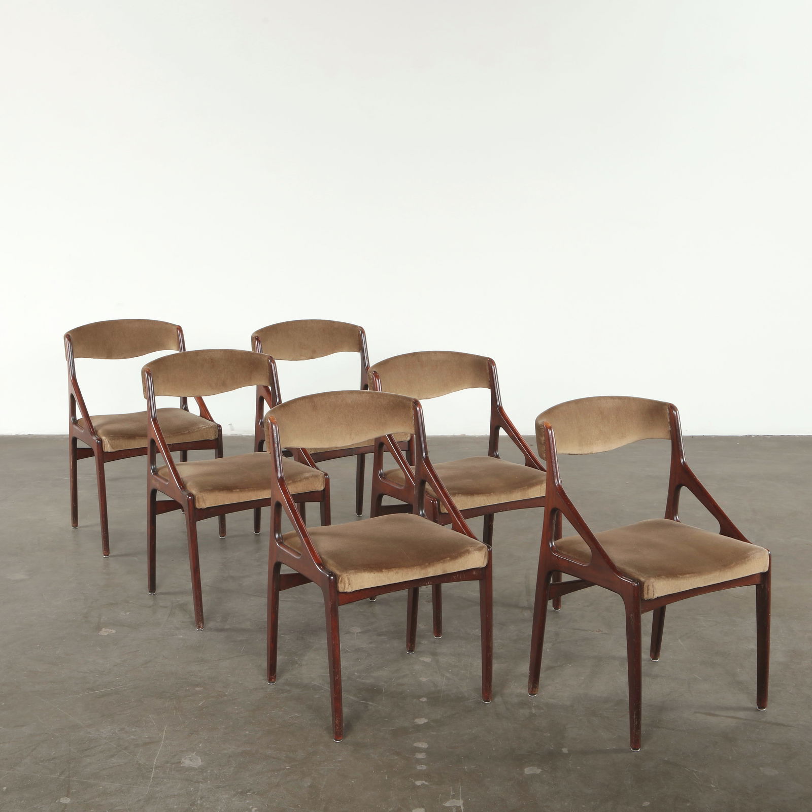 Kai Kristiansen, Set of Six Velvet and Wood Chairs, 1970s: Crafted in sculpted hardwood, this set features Kristiansen signature angled frame with refined, architectural lines. The warm velvet upholstery enhances the organic curvature of the backrest and seat