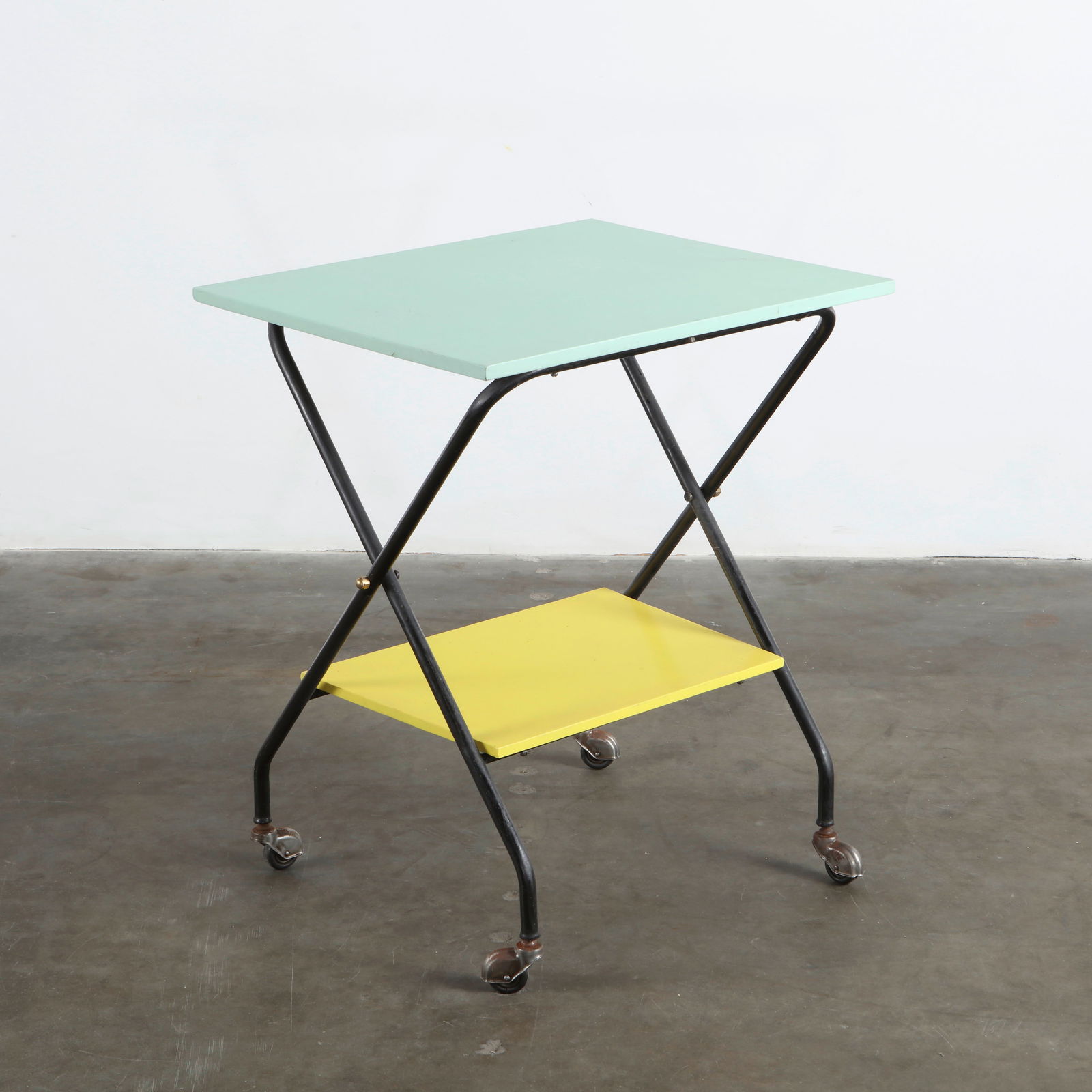 Folding Bar Cart attributed to Mathieu Mategot, 1950s: Modernist bar cart featuring a tubular black metal frame and two lacquered shelves in mint green and yellow. Its lightness and playful color palette reflect Mategot signature approach to metalwork and