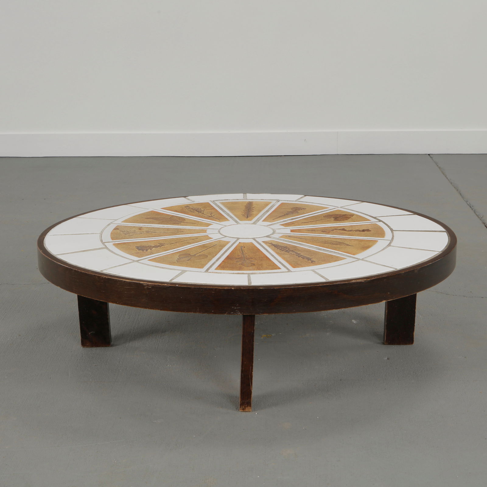 Roger Capron, Oval Garrigue Ceramic Coffee Table, 1960s: Low coffee table with glazed ceramic top decorated with Garrigue motifs, mounted on a stained wooden base. Height: 11.5 in. Width: 40.5 in. Depth: 36 in.