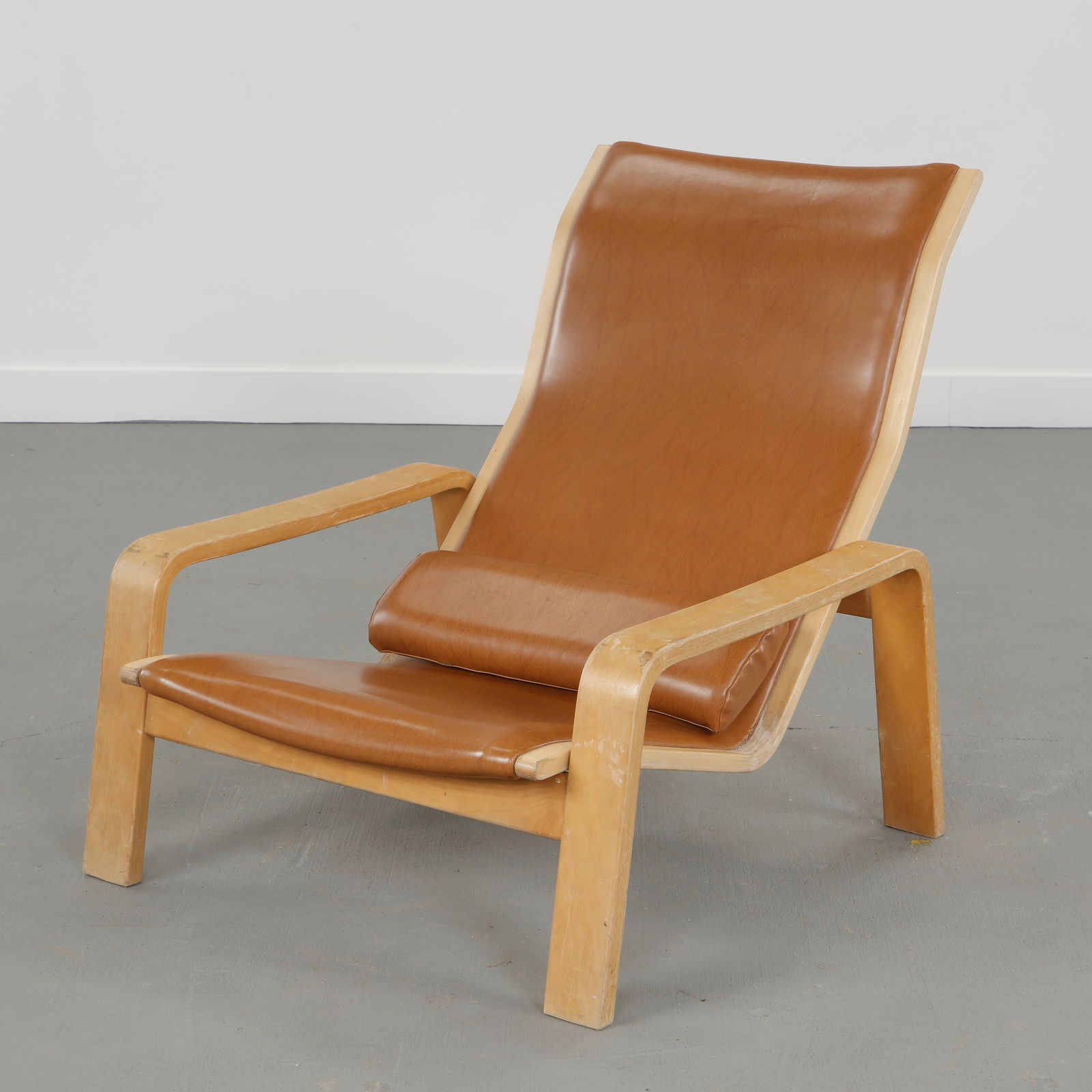 Ilmari Lappalainen for Asko, Leather Pulkka Lounge Chair, Finland, 1960s: Executed in molded birch with original leather upholstery, this Pulkka lounge chair features a low, enveloping profile and gently curved arms. The sculptural shell and patinated leather reflect Lappal