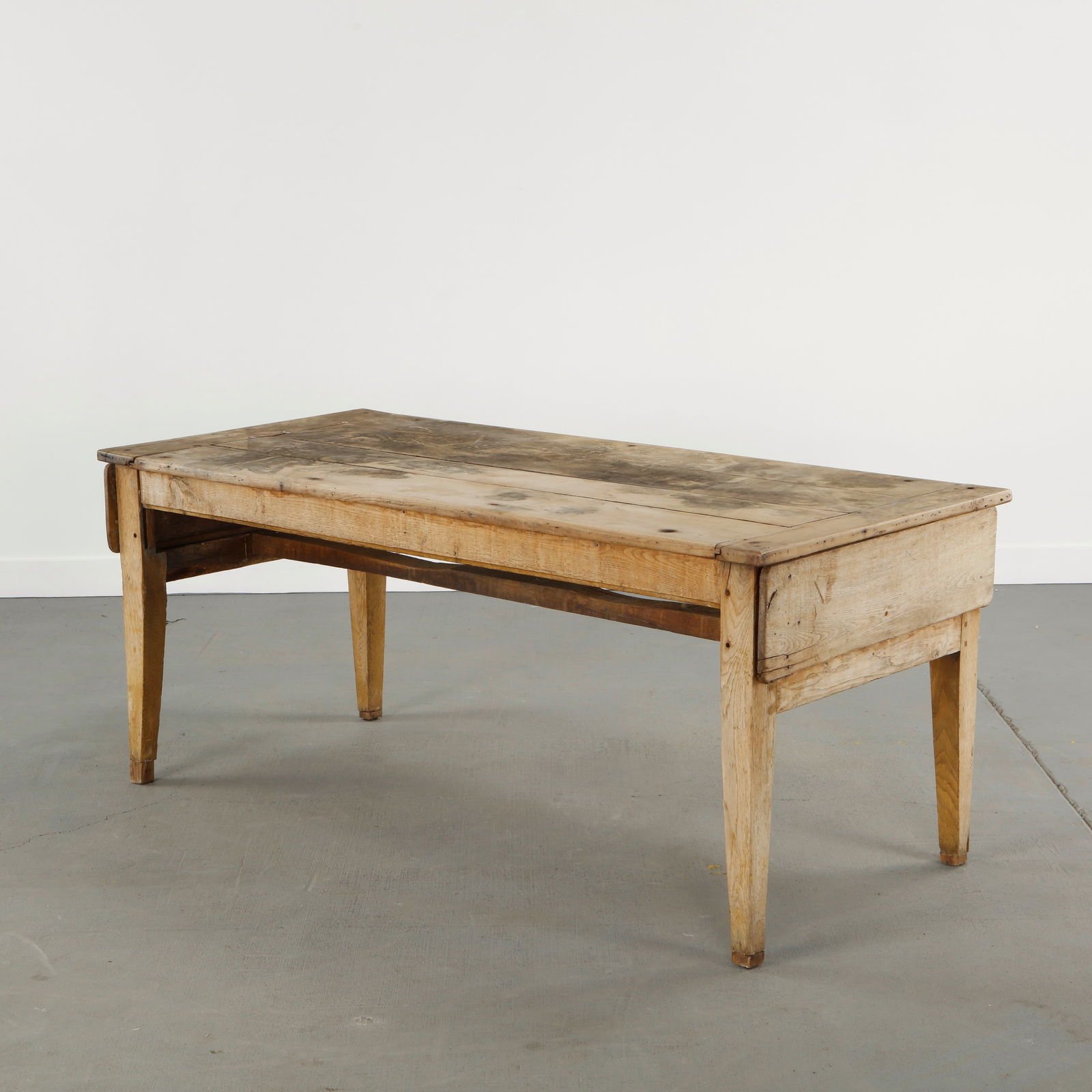 19th Century French Farm Dining Table: A provincial farm dining table crafted from solid wood with a thick plank top and simple trestle base. Bearing a rich patina, this piece reflects rural craftsmanship and utilitarian beauty. Height: 