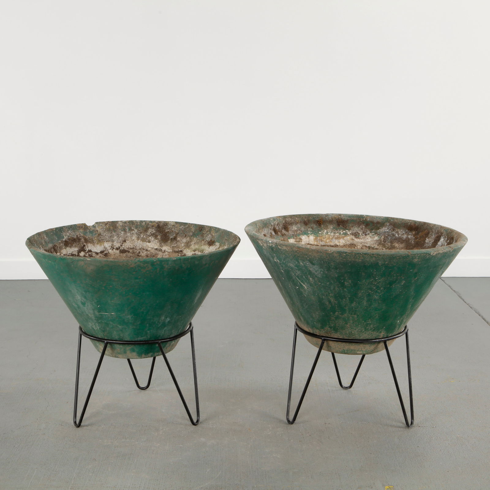 Willy Guhl, Pair of Large Conical Planters on Stands, 1960s: Iconic Willy Guhl silhouettes in compact form, these conical planters rest atop minimalistic metal stands, weathered yet timeless. Height: 26 in. Diameter: 29.5 in. Smaller: Height: 25 in. Diameter: