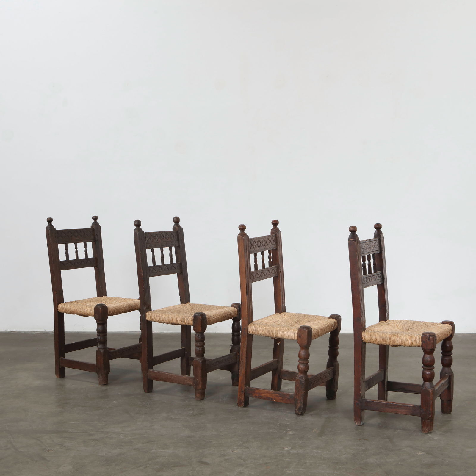 Set of Four Brutalist Oak and Straw Chairs, France, 1950s: Heavily carved oak frames with handwoven straw seats. Honest, rustic construction typical of French mountain craftsmanship. Height: 37 in. Width: 16.5 in. Depth: 16 in. Seat Depth: 15 in. Seat Height: